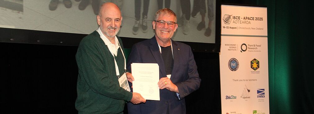 Prof. Dr. Ted Turlings (links) von der Universtät Neuchatel (Schweiz) und vorheriger Präsident der International Society of Chemical Ecology (ISCE) überreicht Prof. Gross die Urkunde.