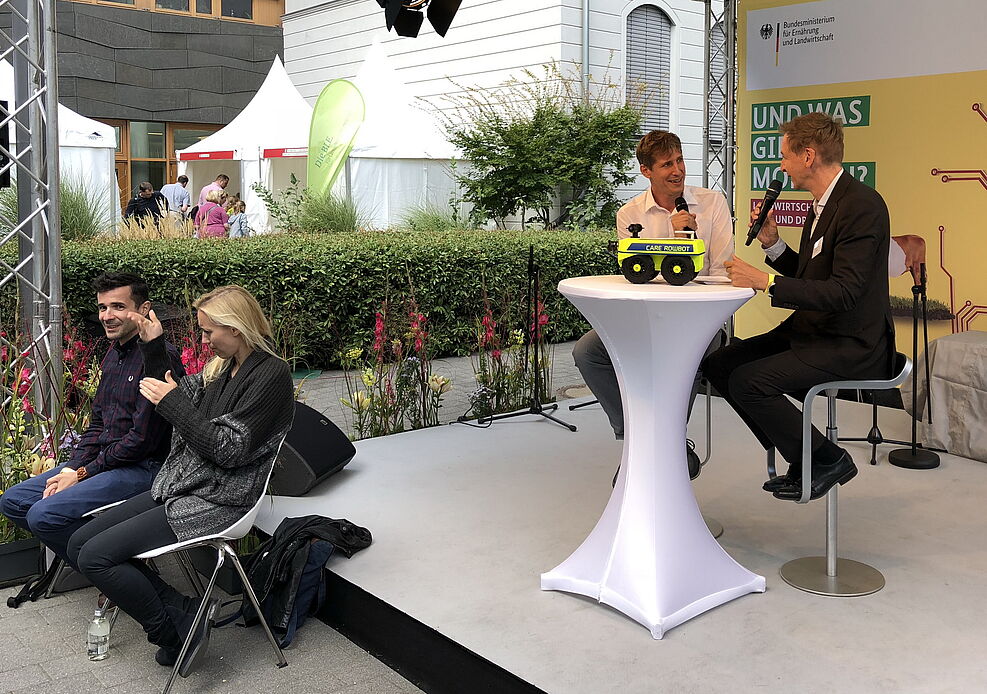 
	Dr. Wegener, Leiter der JKI-Anwendungstechnik erläuterte im Bühnentalk mit RBB-Moderator Marco Seiffert, wie mittels neuer Messtechniken, Software-Schnittstellen, kartierten Flächen und autonom arbeitenden Robotern Präzisionslandwirtschaft betrieben wird.
