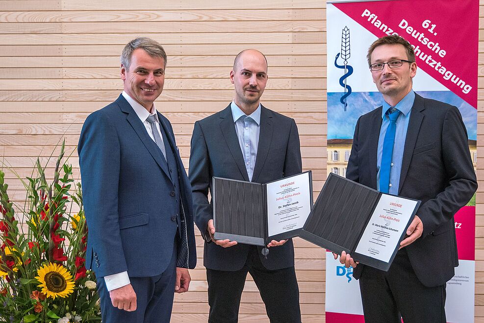 
	Julius-Kühn-Preisträger 2018: Dr. Mario Schumann (re), Dr. Stefan Jacob (Mitte) mit Dr. Gerd Stammler, dem 2. Vorsitzenden der Deutschen Phytomedizinischen Gesellschaft (DPG) (Bildnachweis: Robert Zech)
