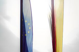 Transluscent flags of Germany and the EU against the bright sky..